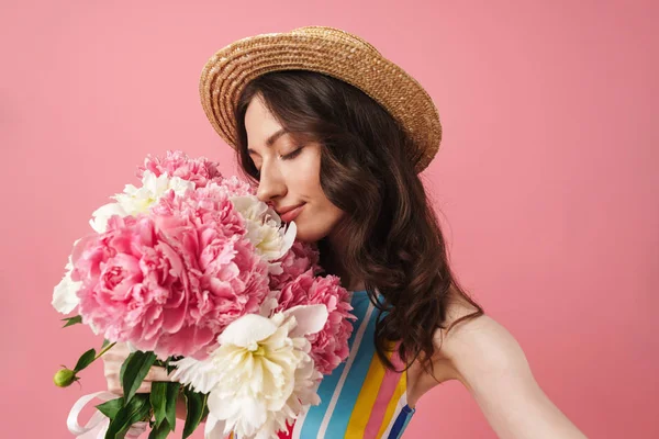 Gelukkig vrolijke glimlachende jonge schattige vrouw poseren geïsoleerd over roze muur achtergrond Holding bloemen. — Stockfoto