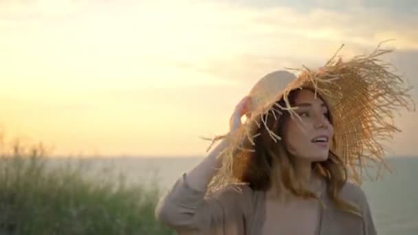 Gülümseyen Genç Bayan Hasır Şapkasını Tutuyor Deniz Kenarında Yürürken Etrafına — Stok video
