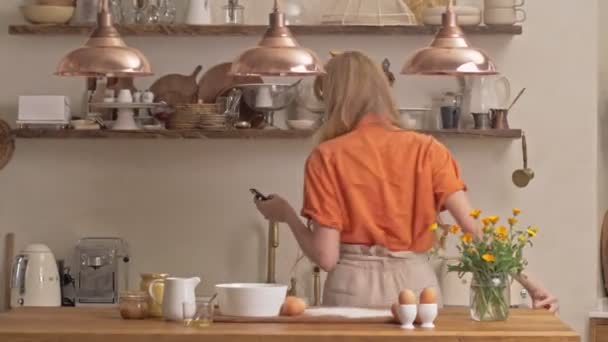 Uzun Kıvırcık Saçlı Neşeli Sarışın Kadın Akıllı Telefonuyla Müzik Dinliyor — Stok video