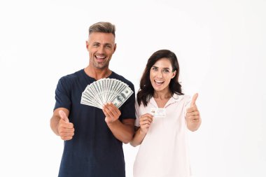 İyimser yetişkin sevgi dolu çift beyaz duvar arka plan üzerinde para ve kredi kartı başparmak gösteren tutarak izole.