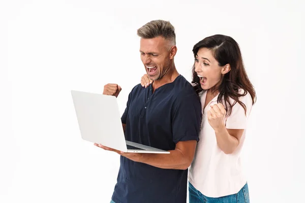 Cheery pozytywny dorosły kochający para na białym tle przez biały ściana tło za pomocą laptopa komputer. — Zdjęcie stockowe