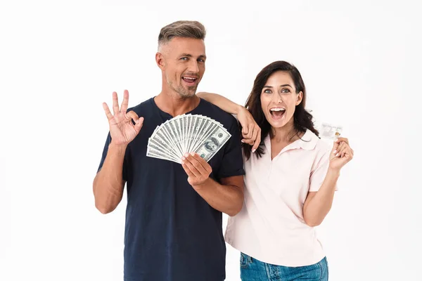 Sorprendido adulto amante pareja aislado sobre blanco pared fondo celebración de dinero y tarjeta de crédito . — Foto de Stock