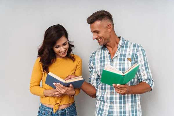 Sorridente adulto amorevole coppia isolato su grigio muro sfondo lettura libro . — Foto Stock