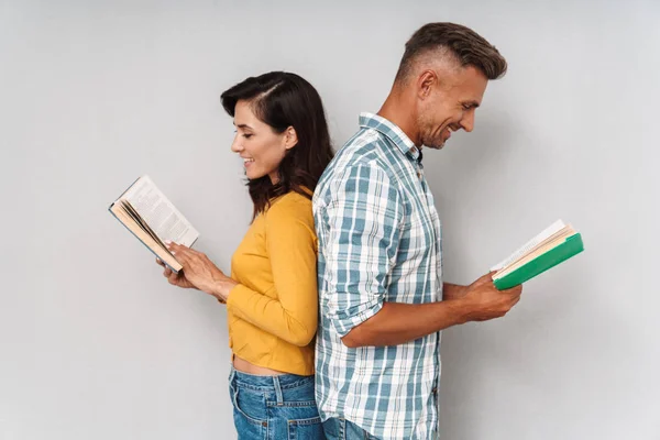Felice sorridente adulto amorevole coppia isolato oltre grigio muro sfondo lettura libri . — Foto Stock
