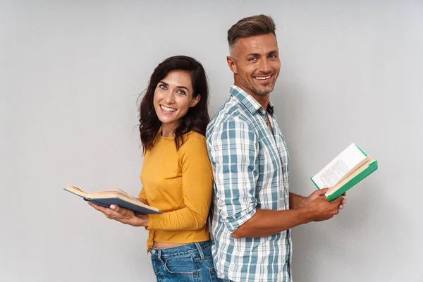 Sorridente adulto amorevole coppia isolato su grigio muro sfondo lettura libro . — Foto Stock