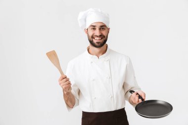 Gülümseyen aşçı üniformalı şefin resmi. Elinde ahşap bir klişeyle.
