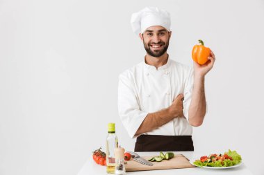 Elinde kağıt tutarken üniformalı yakışıklı şefin resmi.