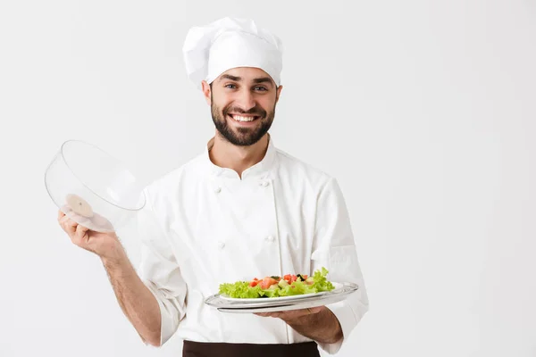 Kép vidám vezető férfi szakács egyenruhában mosolyog és tartja pl — Stock Fotó