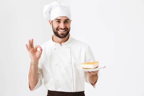 Образ молодого головного чоловіка в кулінарній формі посміхаючись і показуючи дель — стокове фото