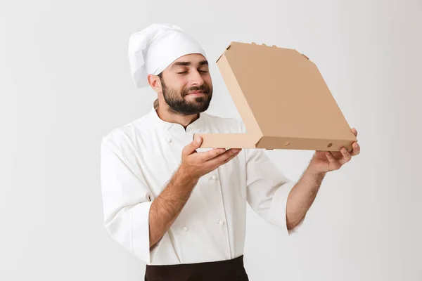 Изображение счастливого пекаря в форме повара, пахнущего во время хранения — стоковое фото