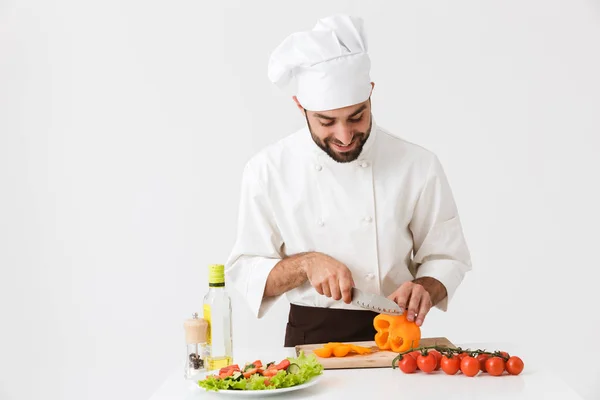 Imagem de homem cozinheiro caucasiano em uniforme sorrindo e corte veget — Fotografia de Stock