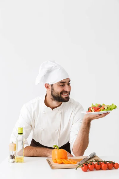 Bild av professionell kock man i uniform ler och håller pl — Stockfoto