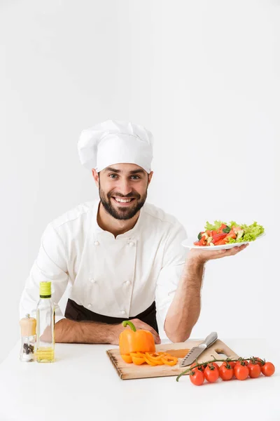 Image of happy cook man in uniform smiling and holding plate wit — Stock Photo, Image