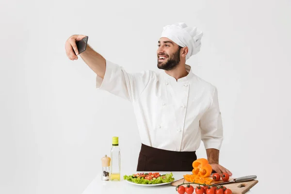 Image of caucasian cook man in uniform taking selfie photo of ve — Stock Photo, Image