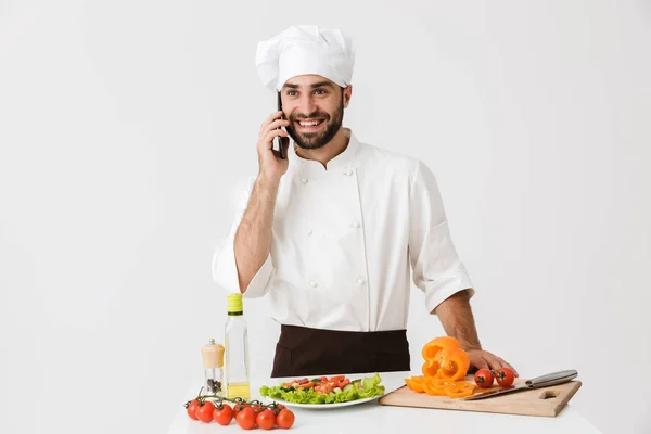 Image of young chef man in uniform smiling and talking on smartp — Stock Photo, Image