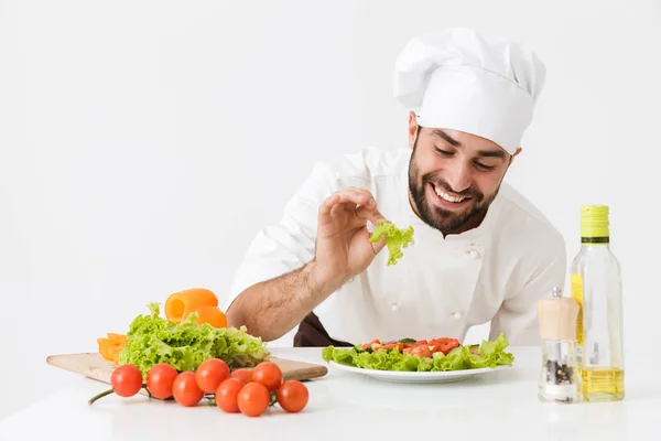 Bild av glad kock man i kock hatt leende och poserar med veg — Stockfoto