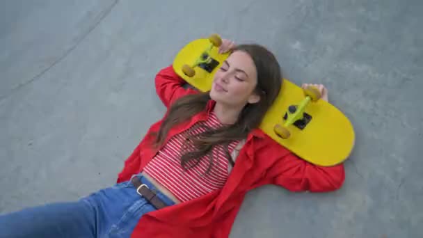 재킷을 스케이트보드에 머리를 스케이트장에 아름답고 소녀가 웃으며 — 비디오