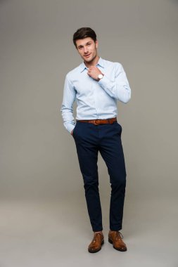 Kol saati takan, elleri cebinde kameraya zehirlenen kendinden emin genç bir adam resmi.