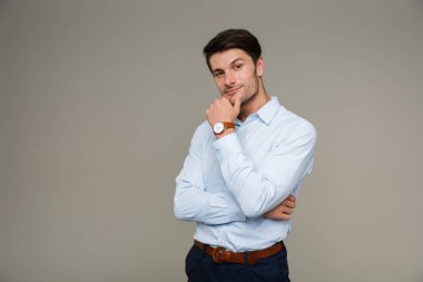 Kol saati takmış, kameraya bakıp çenesine dokunan kendine güvenen ciddi bir adamın görüntüsü.