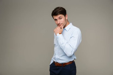 Kol saati takmış, kameraya bakıp çenesine dokunan kendinden emin bir genç resmi.