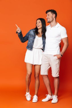 İyimser gülümseyen, çekici, sevgi dolu çift kırmızı duvar arkasında izole bir şekilde poz veriyor..