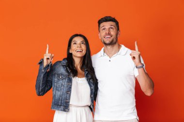 İyimser gülümseyen, çekici, sevgi dolu çift kırmızı duvar arkasında izole bir şekilde poz veriyor..