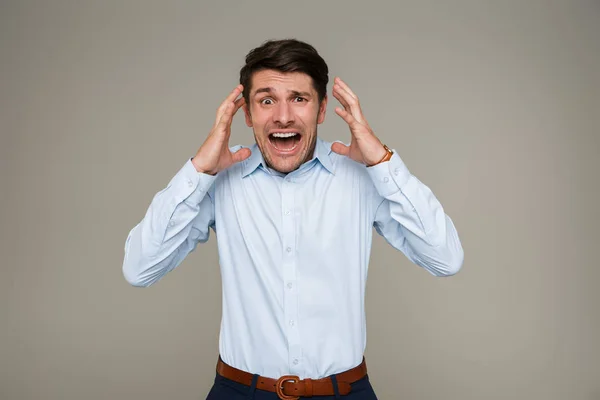 Image of frightened young man wearing formal clothes screaming at camera and throwing up hands — Stock Photo, Image
