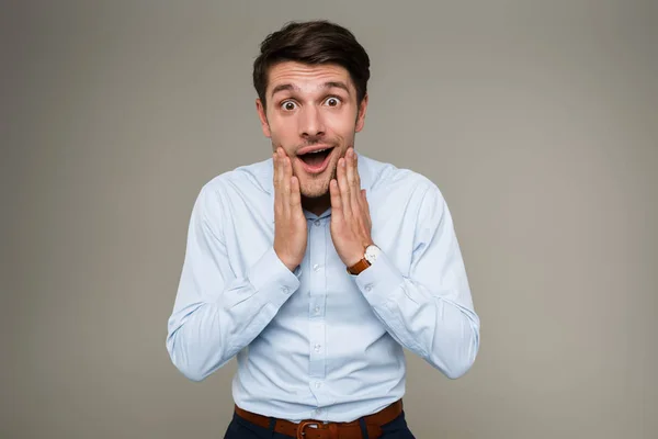 Beeld van verbaasde gelukkige man in formele kleren die naar de camera kijkt en zijn gezicht aanraakt — Stockfoto