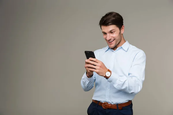 Imagen de un joven feliz usando un reloj de pulsera sonriendo y usando un teléfono celular — Foto de Stock