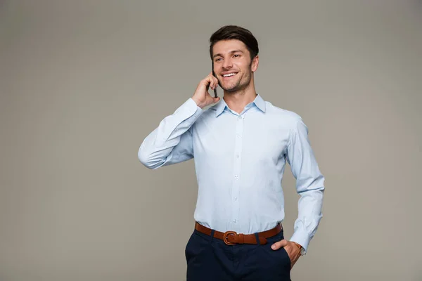 Bild av lycklig maskulin man klädd i formella kläder ler och talar på mobiltelefon — Stockfoto