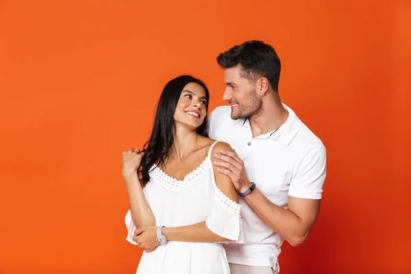 Feliz sorrindo jovem incrível amoroso casal posando isolado sobre vermelho parede fundo abraçando . — Fotografia de Stock