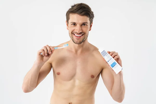 Красивый веселый молодой голый мужчина чистит зубы на белом фоне . — стоковое фото