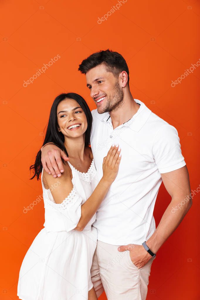 Happy smiling young amazing loving couple posing isolated over red wall background hugging.