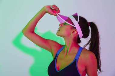 Güzel, konsantre olmuş genç bir spor kadını, ışıklarla izole edilmiş poz veriyor..