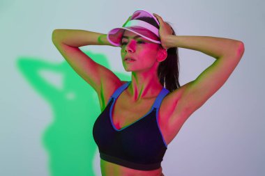 Güzel, konsantre olmuş genç bir spor kadını, ışıklarla izole edilmiş poz veriyor..