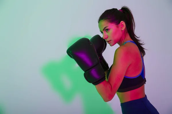 Hermoso boxeador fuerte de la mujer de la aptitud aislado con las luces led del flash hace ejercicios de boxeo . — Foto de Stock