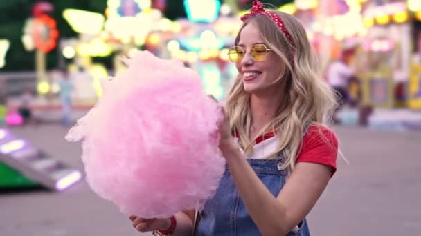 Feliz Joven Rubia Sonriendo Disfrutando Comiendo Hilo Dental Mientras Pasa — Vídeos de Stock