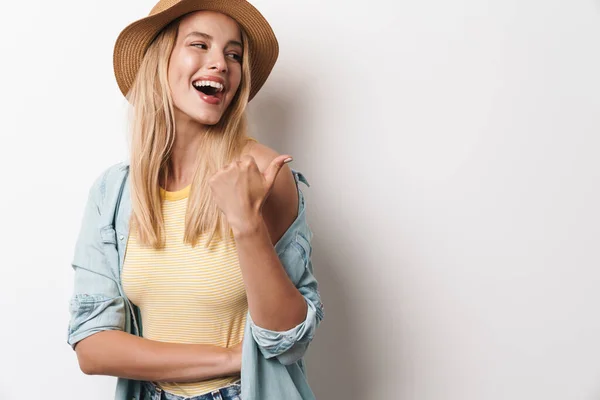 Sorrindo feliz incrível jovem bonita mulher vestindo chapéu posando isolado sobre fundo da parede branca apontando para copyspace . — Fotografia de Stock