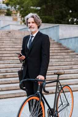 Yakışıklı, kendine güvenen, sakallı, takım elbiseli adam.