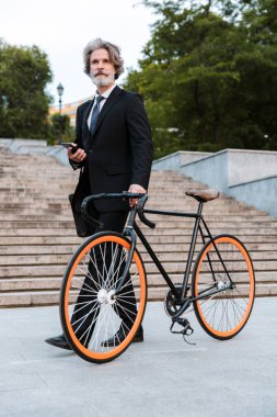 Yakışıklı, kendine güvenen, sakallı, takım elbiseli adam.