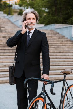 Yakışıklı, kendine güvenen, sakallı, takım elbiseli adam.