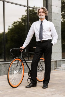 Yakışıklı, kendine güvenen, sakallı, takım elbiseli adam.