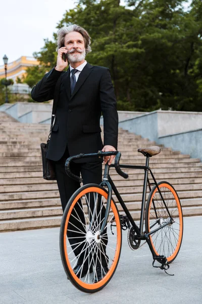 Yakışıklı, kendine güvenen, sakallı, takım elbiseli adam.