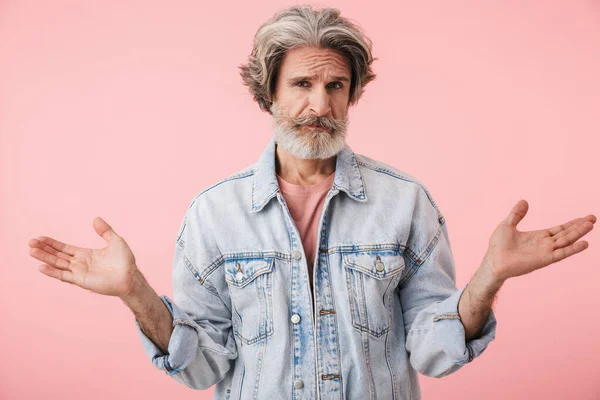 Portret van een verbijsterde oude man met een grijze baard die naar de camera kijkt en handen omhoog gooit — Stockfoto