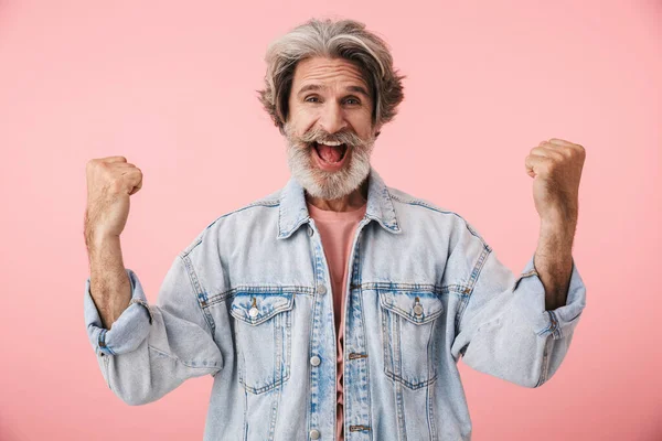 Ritratto di vecchio eccitato con barba grigia che sorride alla telecamera e mostra il gesto del vincitore — Foto Stock