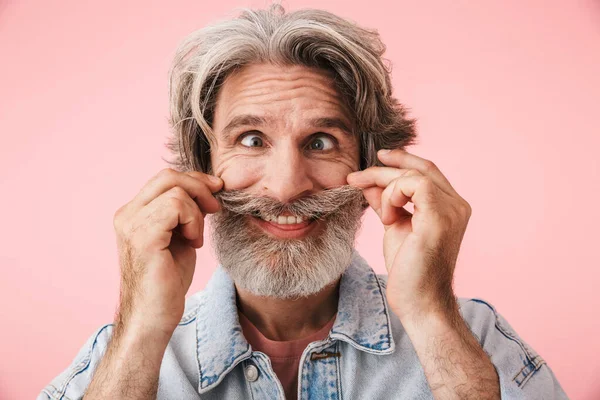 Portrait of cheerful old man with gray beard grimacing and having fun at camera