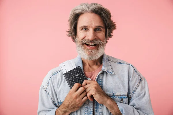 Portrait closeup of joyful old man 70s with gray beard smiling while holding passport and travel ticket