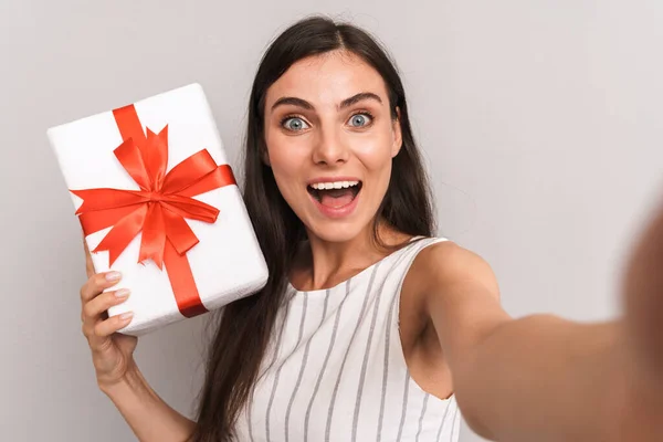 Afbeelding van gelukkig brunette vrouw dragen jurk glimlachen en vasthouden — Stockfoto