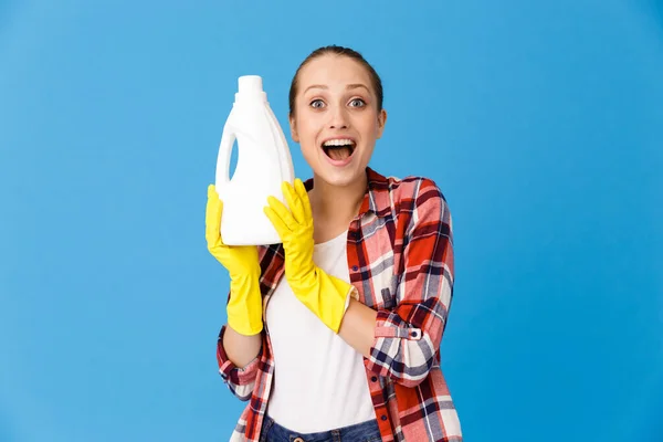 Retrato de jovem dona de casa em luvas de borracha amarela segurando dete — Fotografia de Stock