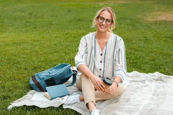 Beautiful young blonde girl relaxing on a lawn at the park — Stock Photo, Image